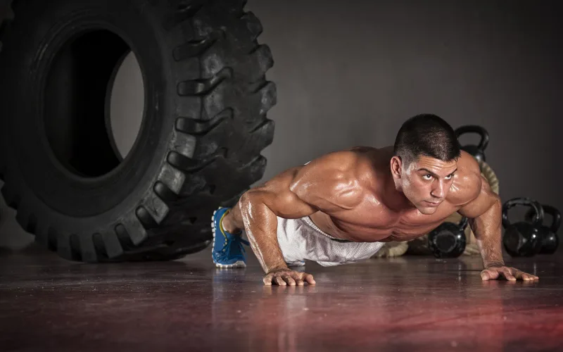 man does a push-up on the floor of a garage gym