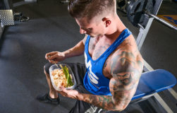 Guy bulking by eating meal in the gym