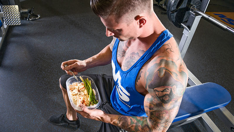 Guy bulking by eating meal in the gym